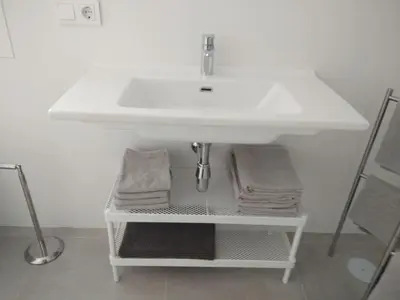 a bathroom sink with towels on a shelf under it at CHALET ARRILUCE Plaza de parking gratis en la playa in Chiclana de la Frontera