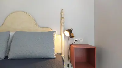a bedroom with a bed with a blue pillow and a lamp at Sherryflat Claveles - Parking in Jerez de la Frontera
