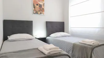 two beds in a room with white towels on them at Sherryflat Claveles - Parking in Jerez de la Frontera