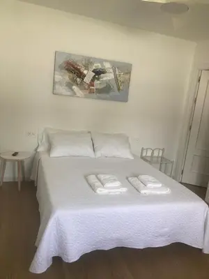 a bedroom with a white bed with two towels at Alojamiento Rural Al´Mare in Conil de la Frontera