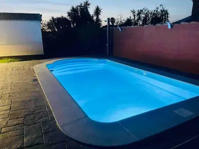 a large blue swimming pool in a backyard at Alquiler de casa Vacacional in Chiclana de la Frontera