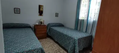 a bedroom with two beds and a dresser and a window at Casa con piscina privada y jardín in Chiclana de la Frontera