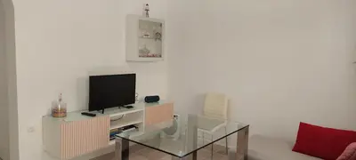 a living room with a tv and a glass table at Casa con piscina privada y jardín in Chiclana de la Frontera
