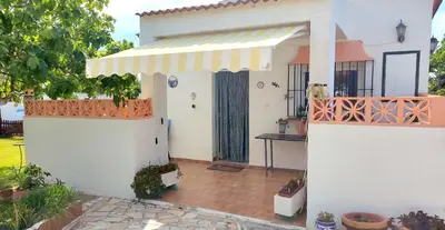 a white house with a gate and a porch at Casa con piscina privada y jardín in Chiclana de la Frontera