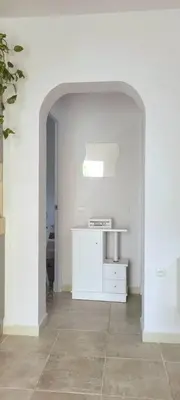 a white room with an archway and a white kitchen at Casa con piscina privada y jardín in Chiclana de la Frontera