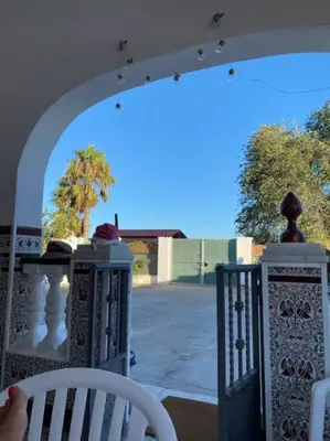 a person sitting on a porch with a white chair at Casa im andalusischen Look in der Nähe von Chipiona in Costa Ballena