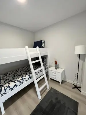 a white bedroom with a bunk bed and a ladder at Piso Palacios in El Puerto de Santa María