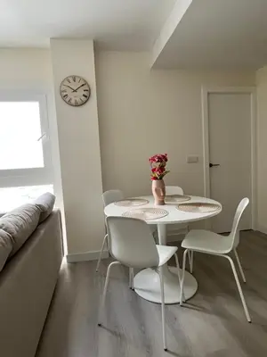 a dining room with a table and chairs and a clock at Piso Palacios in El Puerto de Santa María