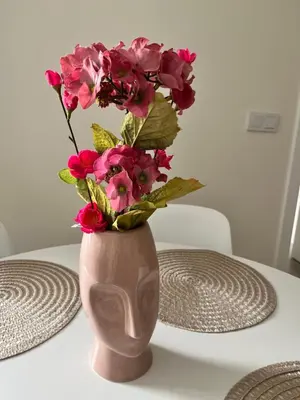 a vase with pink flowers in it on a table at Piso Palacios in El Puerto de Santa María